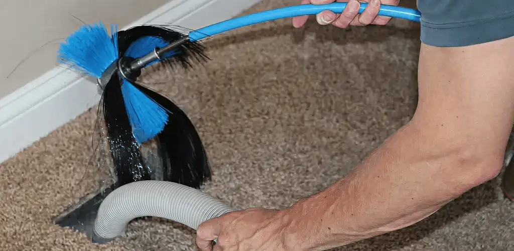 Dryer vent cleaning technician brushing lint from a vent line in Wilmington, NC