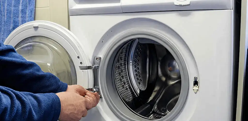 Washing machine repair handyman checking a front-load washer door and latch in Wilmington, NC
