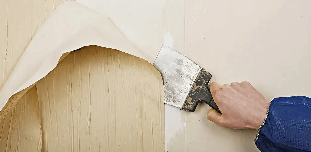 Handyman removing wallpaper with a scraper for wall preparation in Wilmington, NC