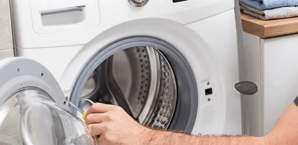 Handyman repairing a front-load washing machine and inspecting the drum in Wilmington, NC