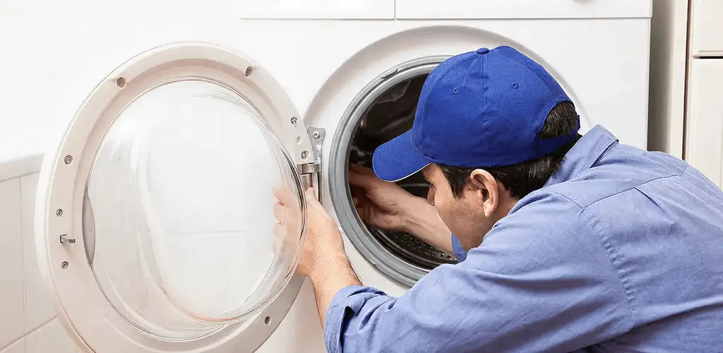 Washing machine repair handyman inspecting a front-load washer drum in Wilmington, NC