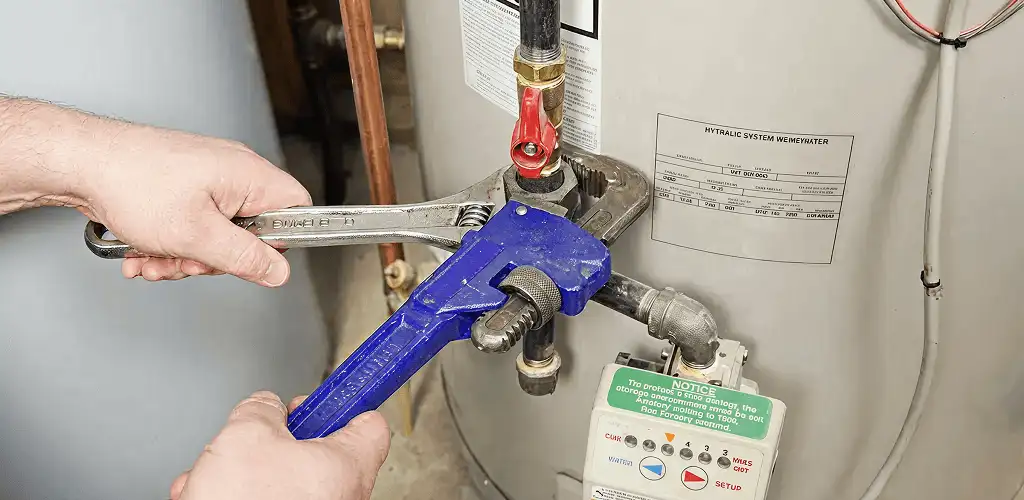 Water heater repair technician tightening the shutoff valve and supply line in Wilmington, NC